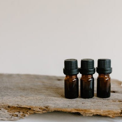 Three small brown glass bottles with black caps on a wooden surface.