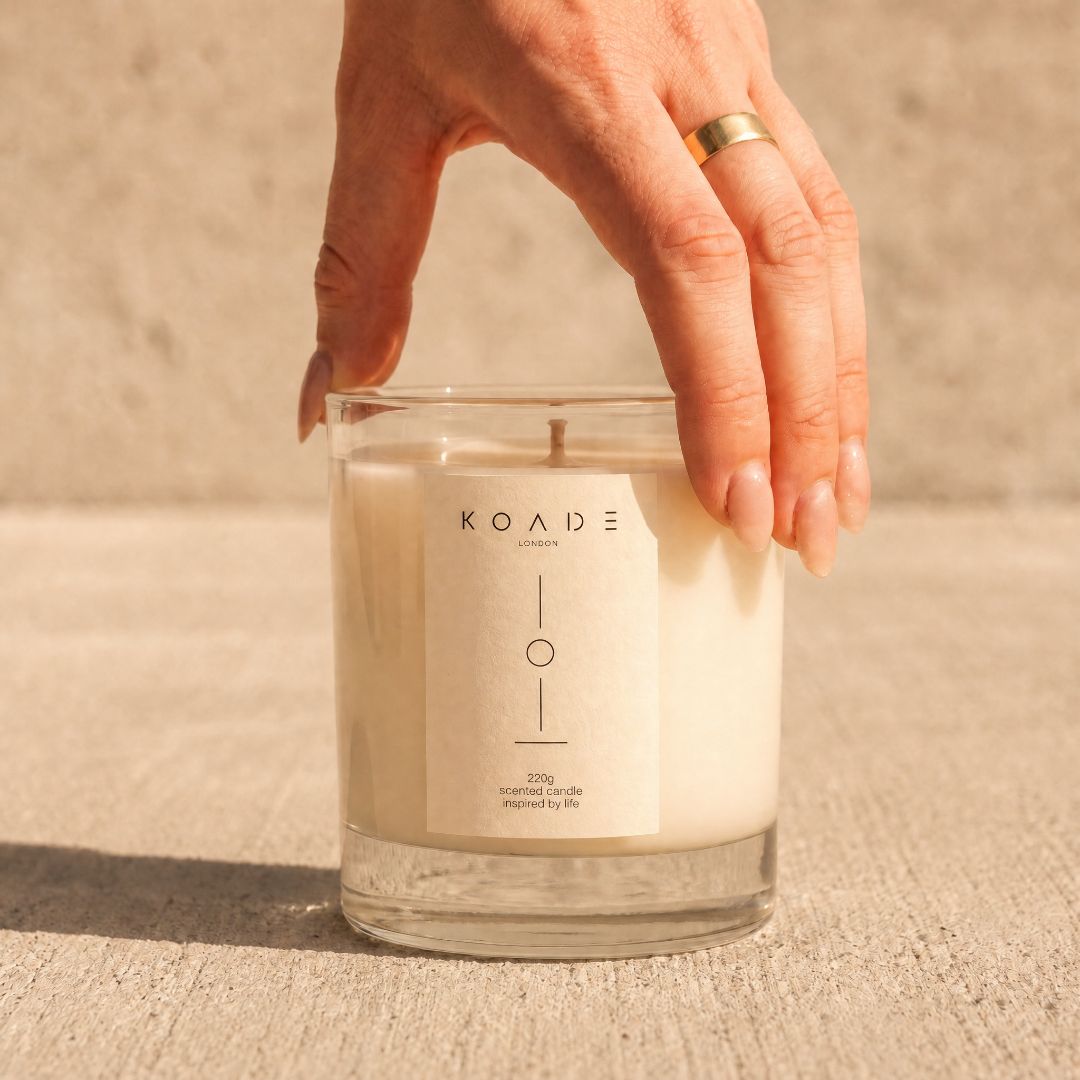 Hand holding a KOADE LONDON candle on a textured surface
