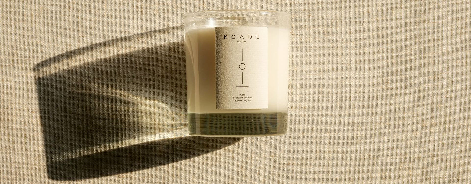 Candle with a visible brand label on a textured beige background