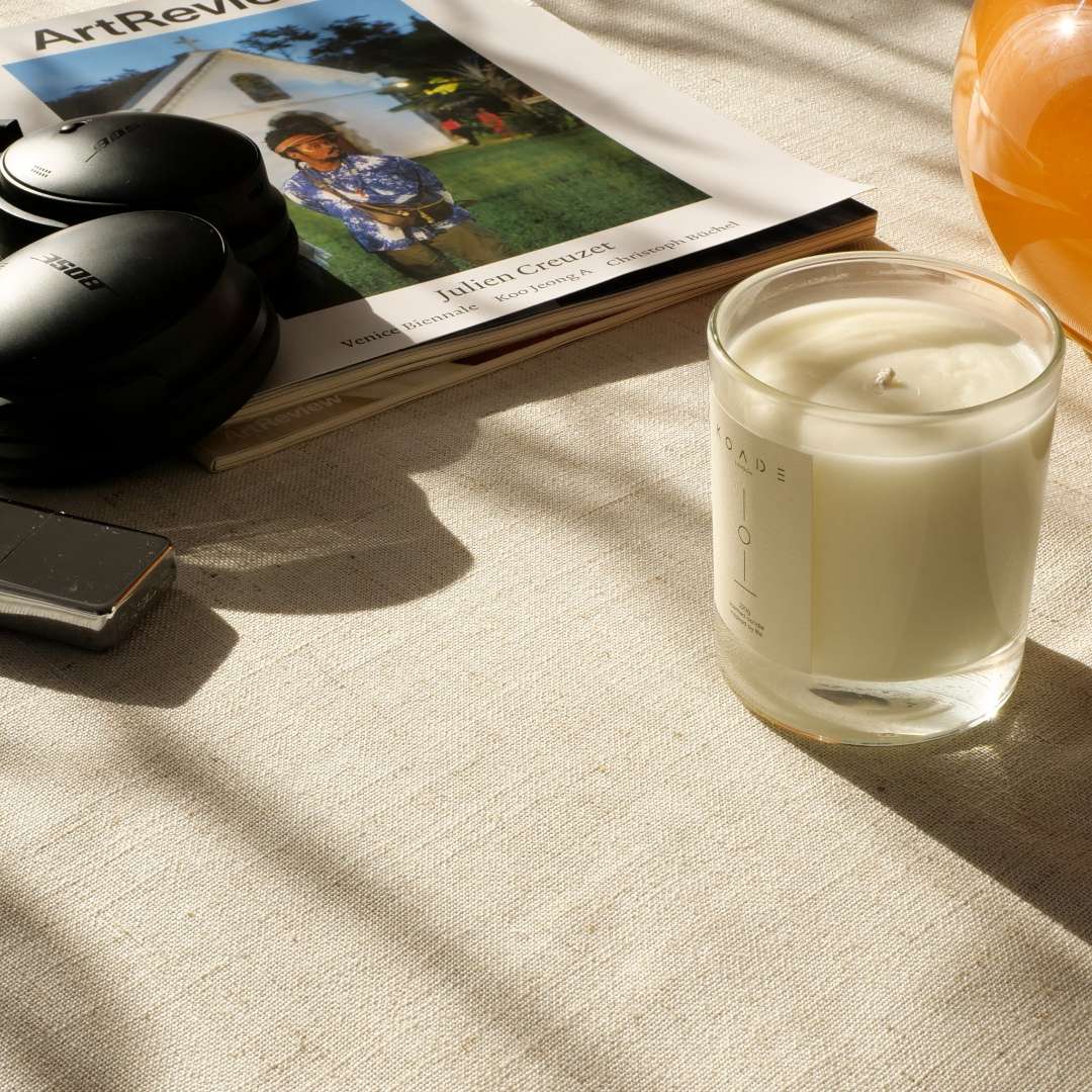 Candle on a table with a magazine and phone in the background