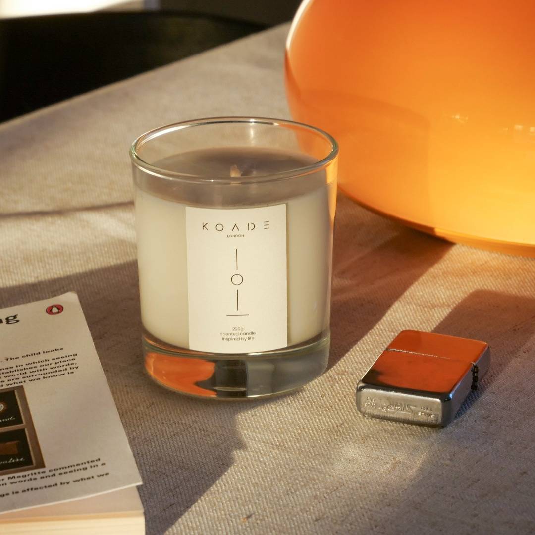 KOADE glass candle in sunlight next to a book