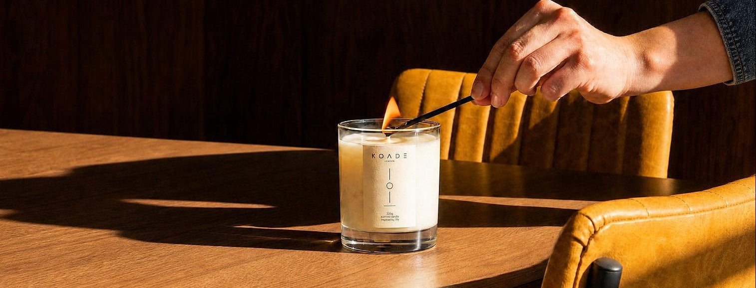 Hand lighting a candle on a wooden table with a dark background