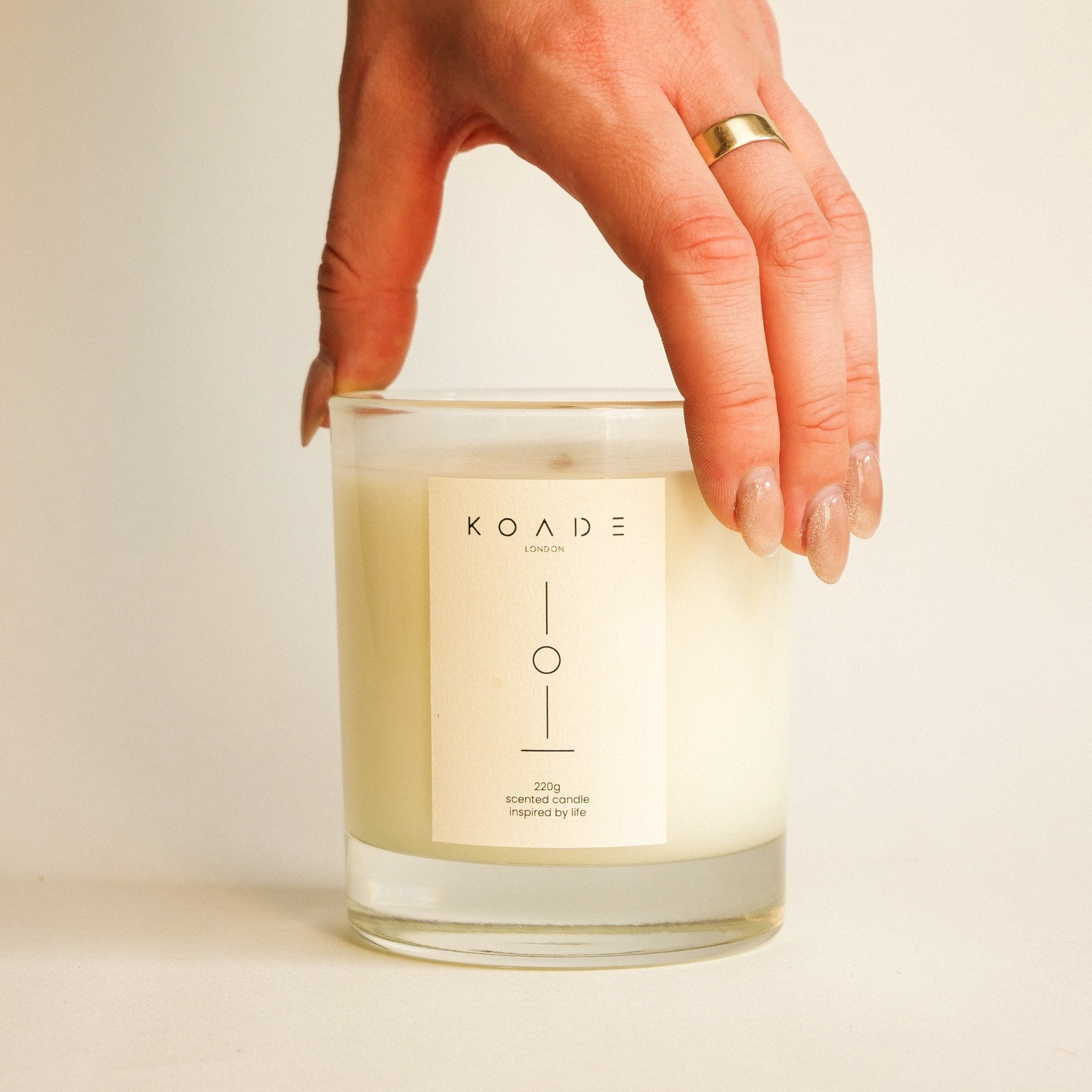 Hand holding a KOADE London candle against a neutral background