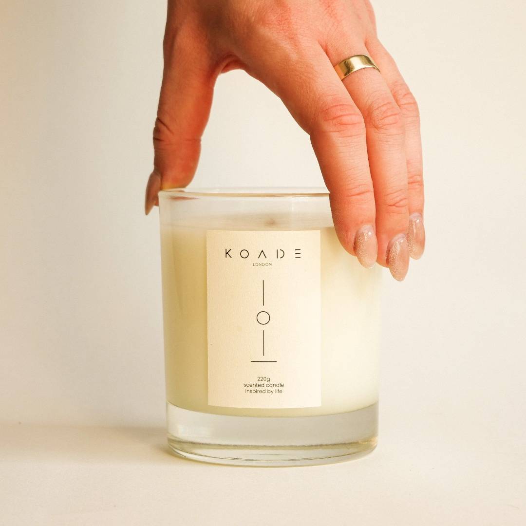Hand holding a KOADE London candle against a neutral background