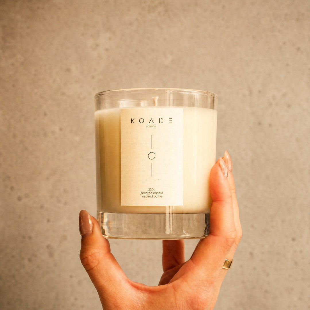 Hand holding a KOADE candle against a neutral background