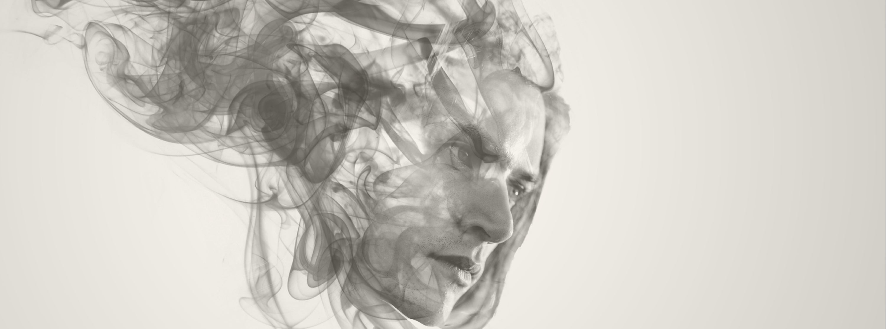 Artistic depiction of a face formed by smoke or ink on a light background