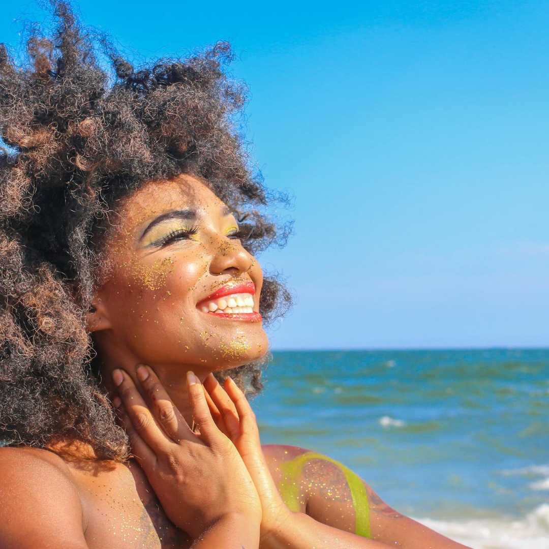 Lady smiling in the sunshine on a beach