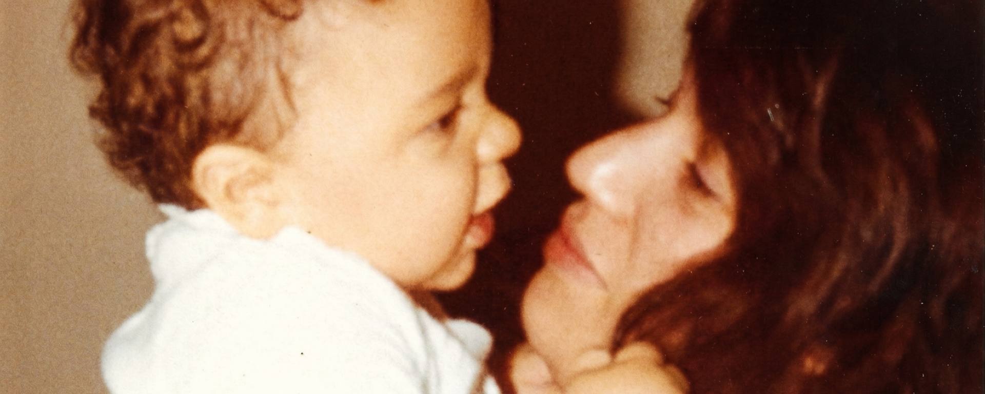 Close-up of a child and an adult facing each other with a neutral background