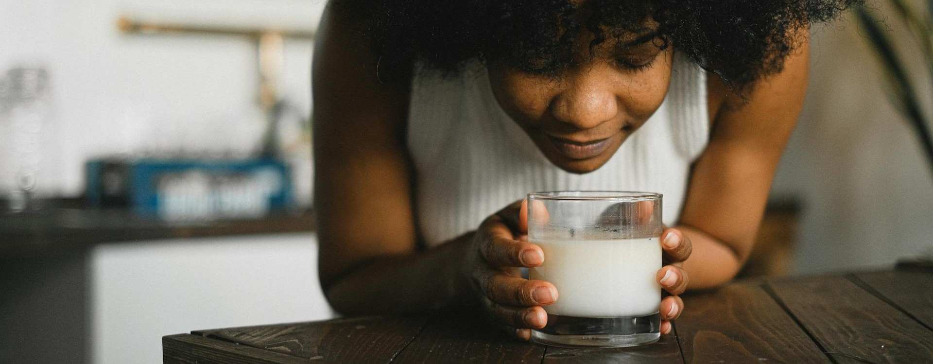 Person holding a glass of milk in a kitchen setting