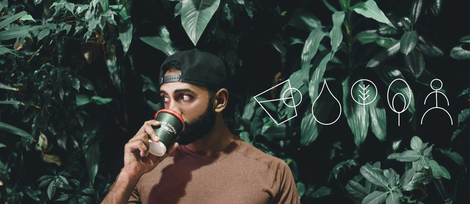 Man smelling a coffee cup in a leafy green setting with a brand logo overlay.