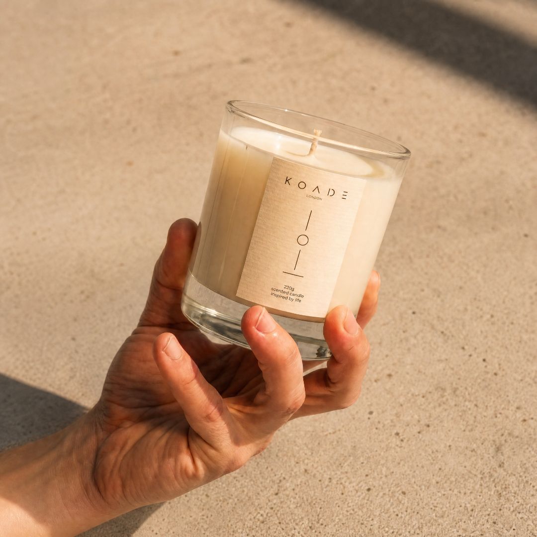 Hand holding a KOADE candle against a neutral background