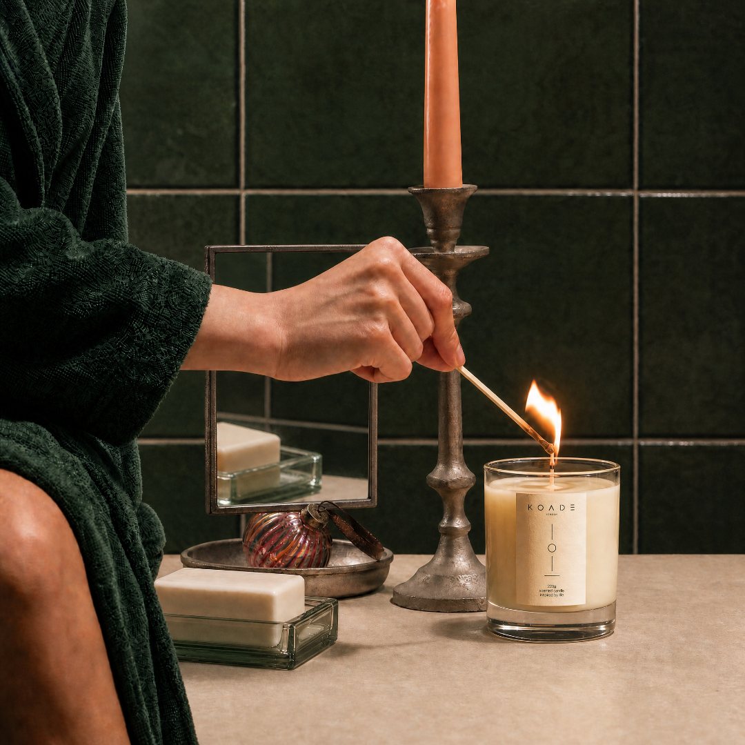 Person lighting a candle with a match in a bathroom setting.