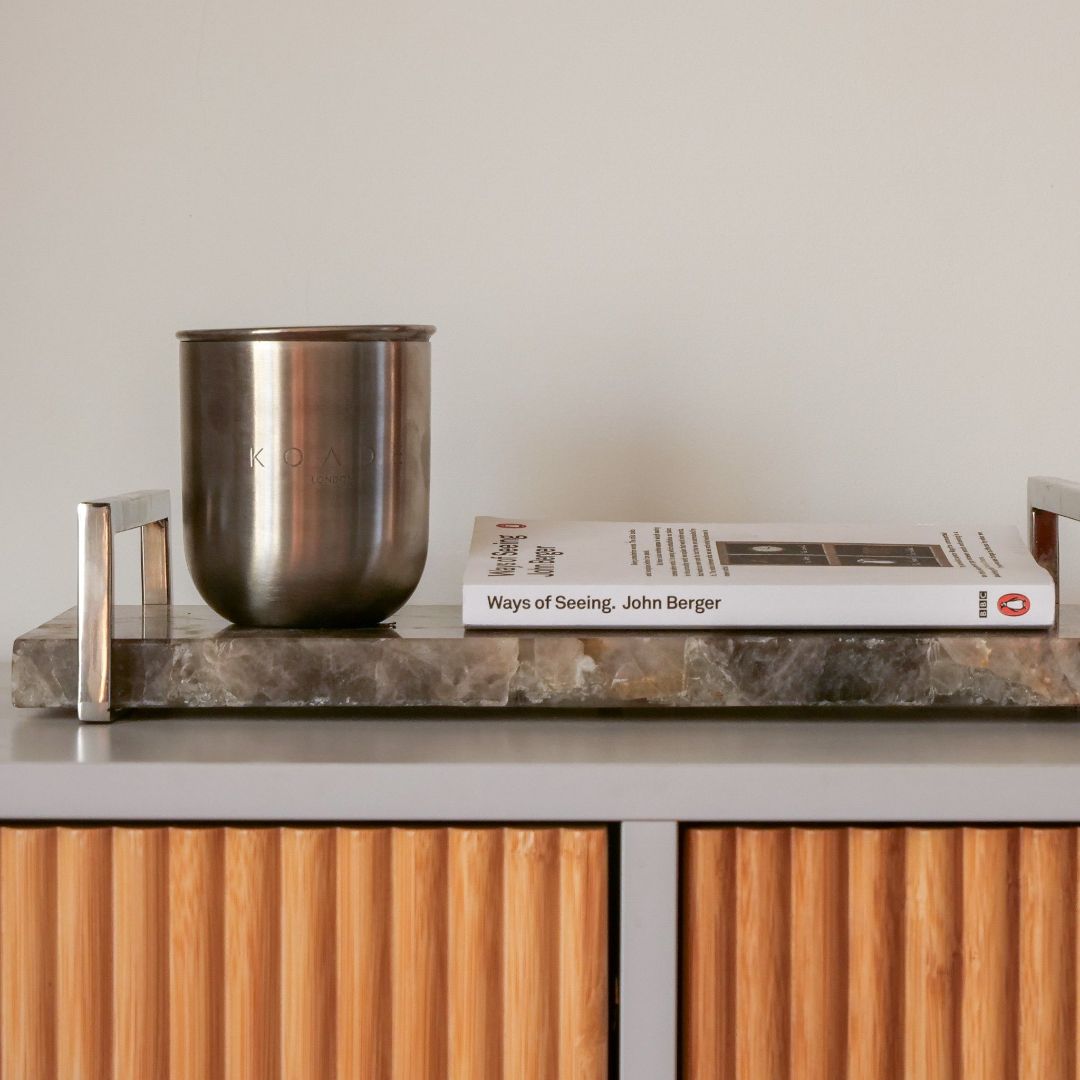 KOADE steel candle on a cabinet next to a book
