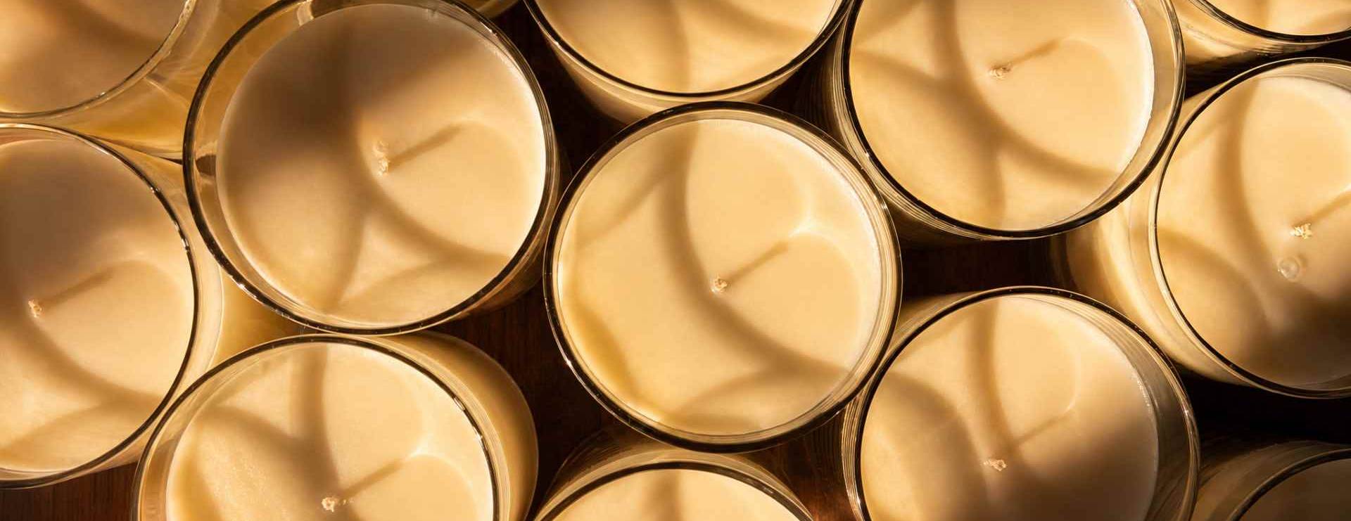 Close-up of multiple beige candles in metal containers.
