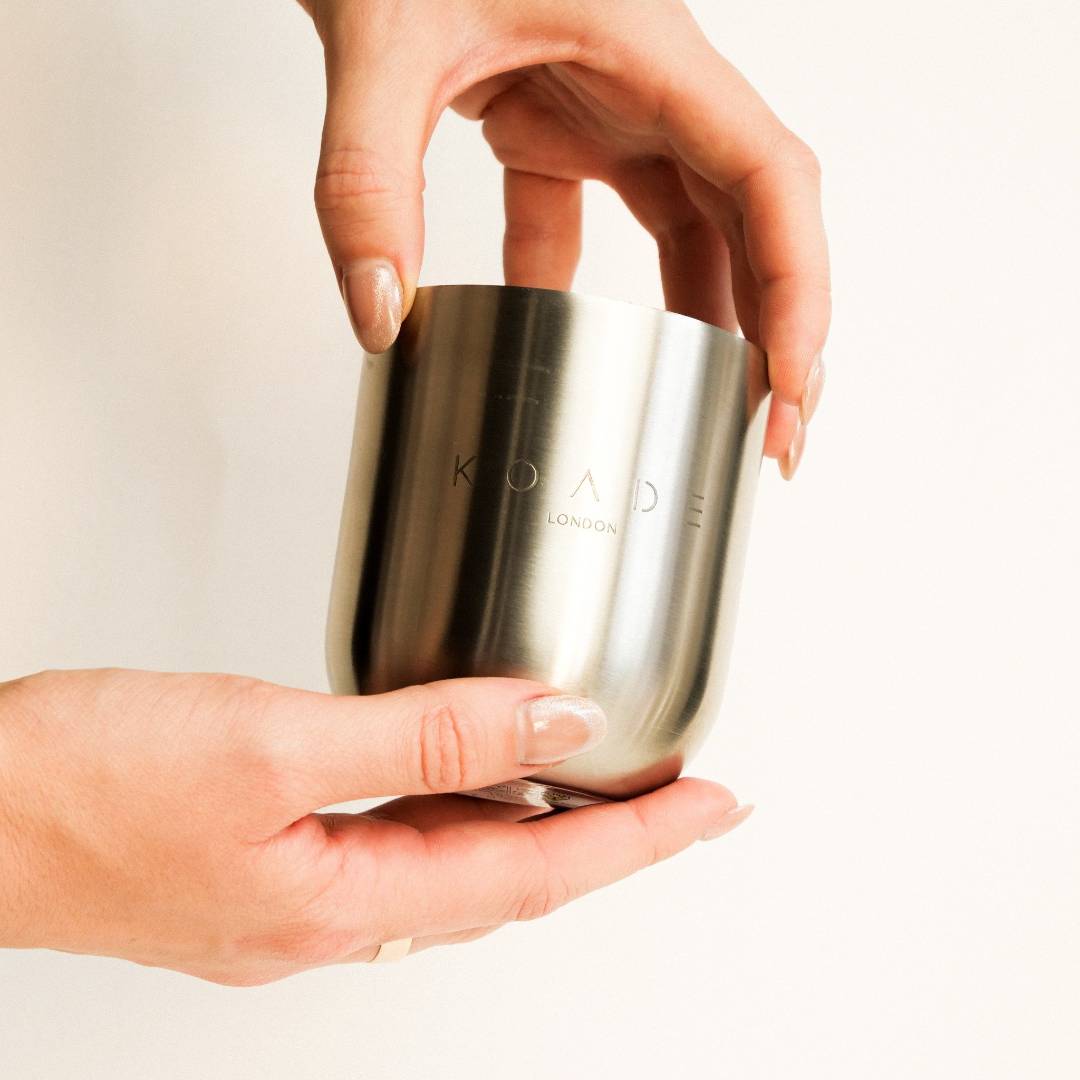 Silver cylindrical container held by a hand with a plain background