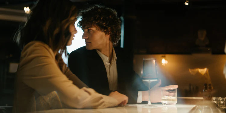 Two people sitting closely together in a dimly lit room, possibly a bar or restaurant.