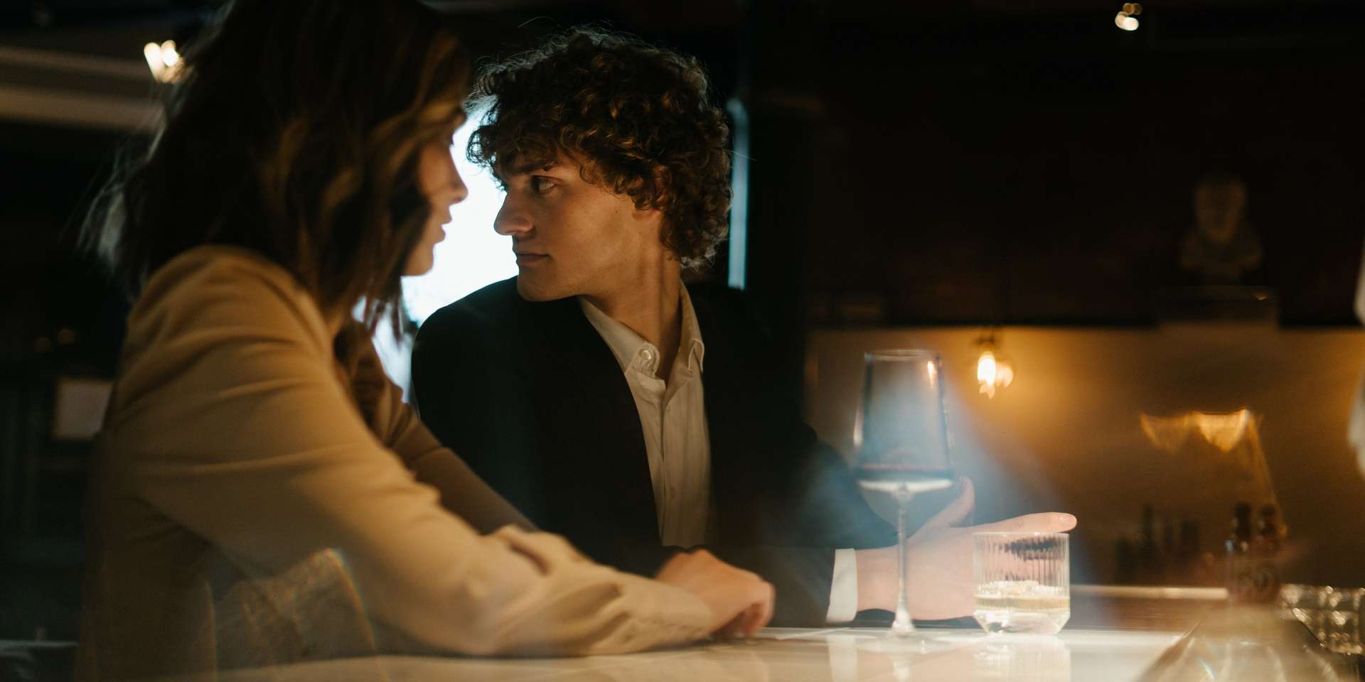 Two people sitting closely together at a bar with dim lighting.